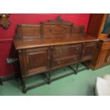In the manner of 'Waring & Gillows' an Edwardian oak sideboard the raised back with carved and