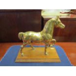 A brass figure of a prancing horse on a hardwood base. 24cm high