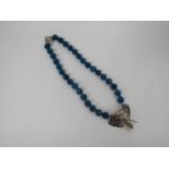 Bill Skinner faceted blue bead necklace with a white metal elephants head pendant and clasp