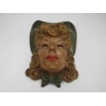 An Art Deco wall mask of female with blonde curly hair in a green hat, wearing red lipstick and a