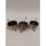 Three Georgian silver table salts, each with Bristol blue glass liners, shell relief hoof feet, with