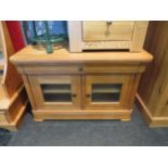 An oak cabinet, single drawer over cupboard doors revealing shelved interior. 57cm high x 88cm