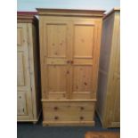 A natural pine compactum wardrobe, the two doors over two drawers, 200cm high x 104cm wide x 55cm