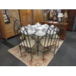 A circular glass table on iron base with a set of six iron frame arch chairs