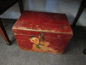 A red painted wooden box, decorated with a small child and a rodent. 46 x 32 x 31cm