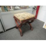 A pair of walnut 'X' frame stools with lion mask carved decoration on claw feet, upholstered seats