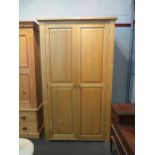 A natural oak two door wardrobe, 200cm high x 118cm wide x 64cm deep