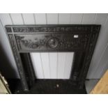 A highly decorative cast iron fire surround with figural roundel