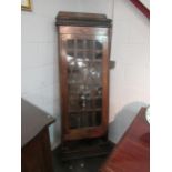 An oak cupboard with glazed door, shelved interior over open undershelf, ornately carved sides and