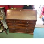 A country house oak bureau with mahogany crossbanding the fitted interior and fall with key over two