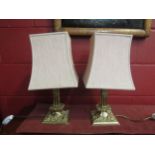 A pair of brass table lamp bases with cherubic relief