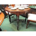 A walnut octagonal occasional table with turned cross supports and stretcher on ceramic castors,