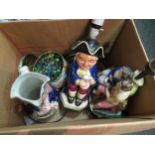 A box containing a tin of marbles, figural ceramic table lamp, Toby jug and lamp