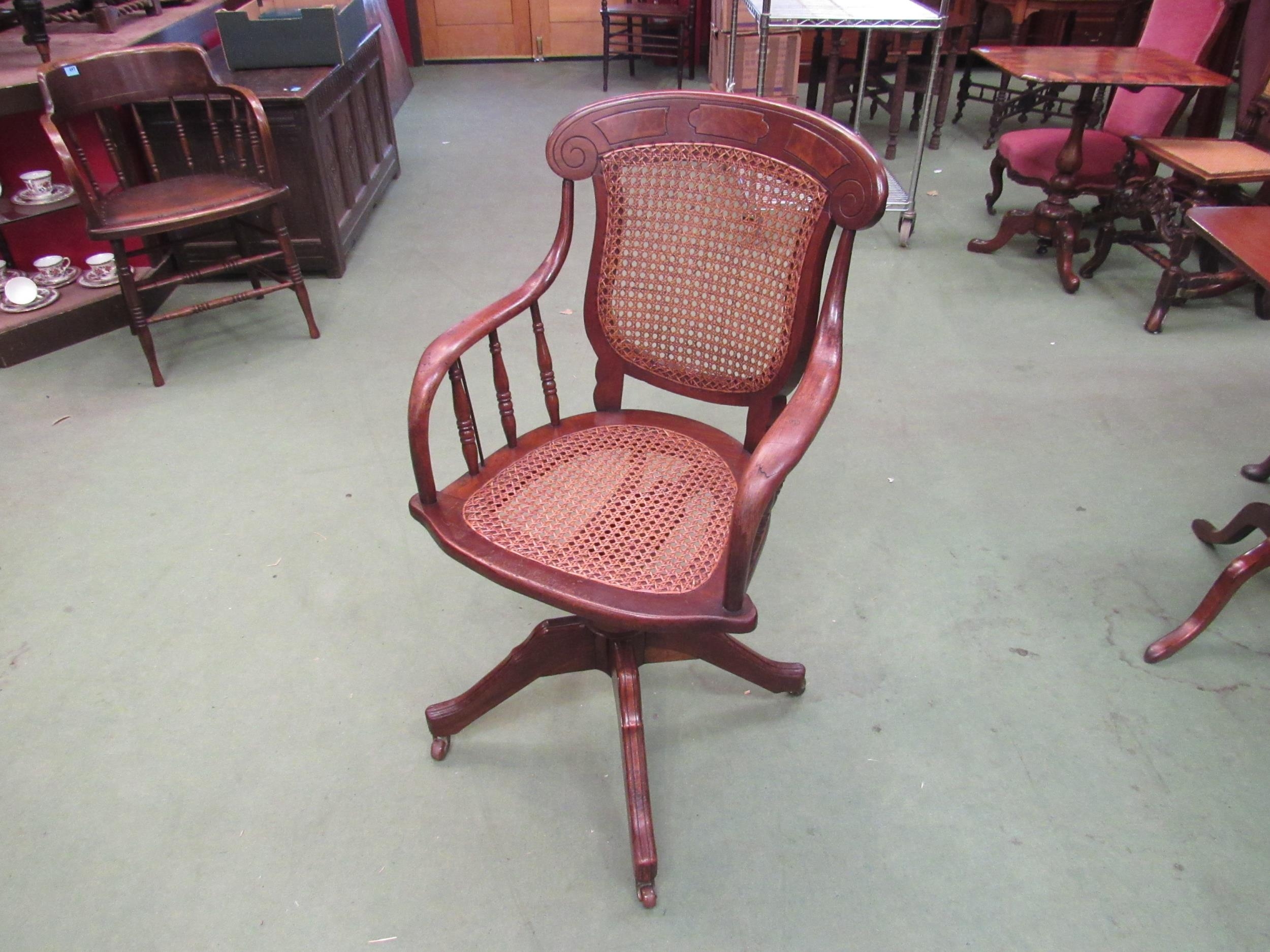 A circa 1900 oak and mahogany cane seat and backrest revolving office chair with walnut decoration