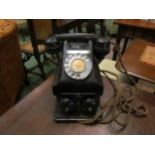A vintage black bakelite telephone resting upon a plinth containing bells