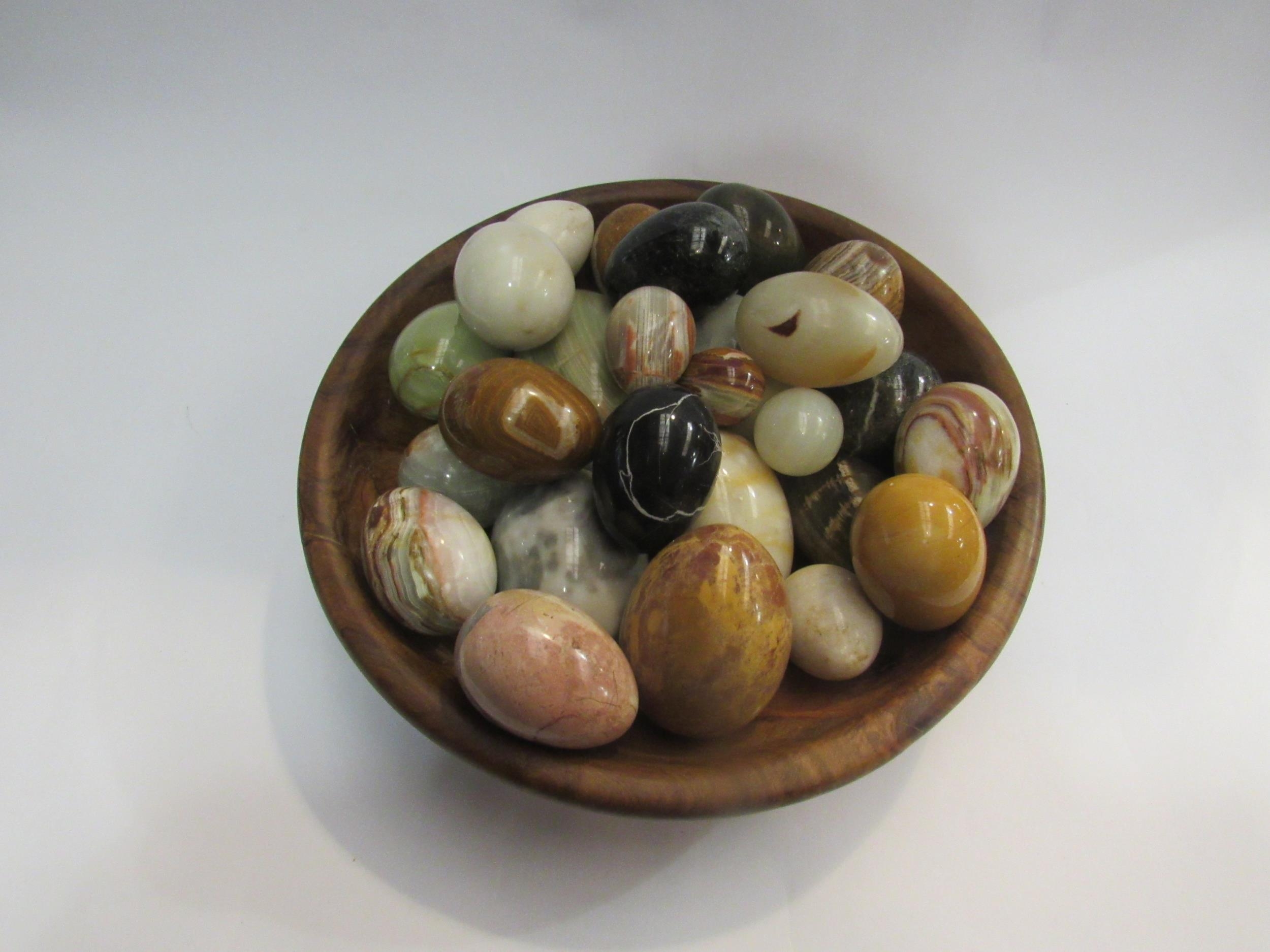 A wooden bowl containing a quantity of polished stone eggs