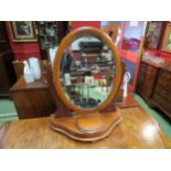 A walnut oval dressing table bevel edged mirror with lidded compartment to base on bun feet