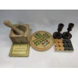 A wooden pestal and mortar, solitaire set, hardwood draughts and wooden candle holders
