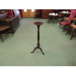 A mahogany torchere the dished circular top on turned and carved fluted column, decorative brass