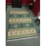 A green and cream Kilim rug decorated with geometric patterns, tasselled ends, 300cm x 200cm
