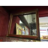 A red and gilt ornately framed wall mirror with bevel edge, 53.5cm high x 63.5cm wide