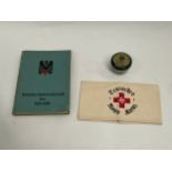 A German 1942 Red Cross book together with German Red Cross ointment and a replica armband