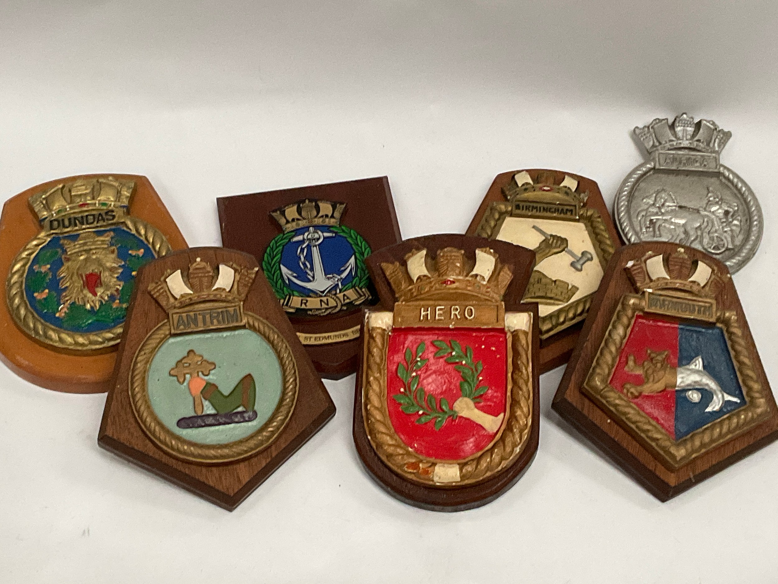 A box of ship’s crests: HMS Hero, Yarmouth, Antrim, Birmingham, Auriga, Dundas and RNA Bury St.