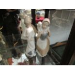 Two Nao figures of girls, one with lamb on her shoulders
