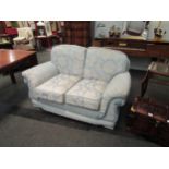 A classic style two seater sofa, rope trim, loose cushions, pale blue floral upholstery, Life