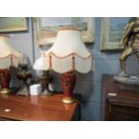 A pair of red and gilt floral design table lamps with tasselled shades