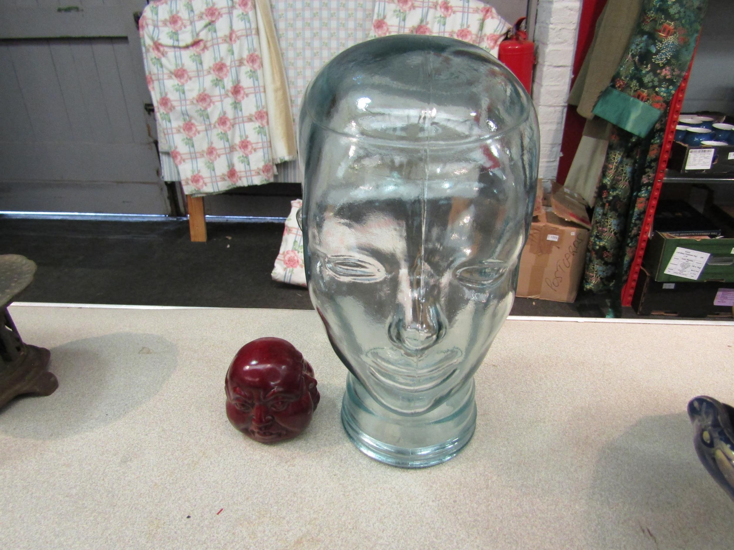 A glass head, 29cm high, together with a buddha head (2)