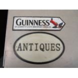 A reproduction Guinness street sign, 37cm long, and a cast iron "Antiques" sign, 34cm long