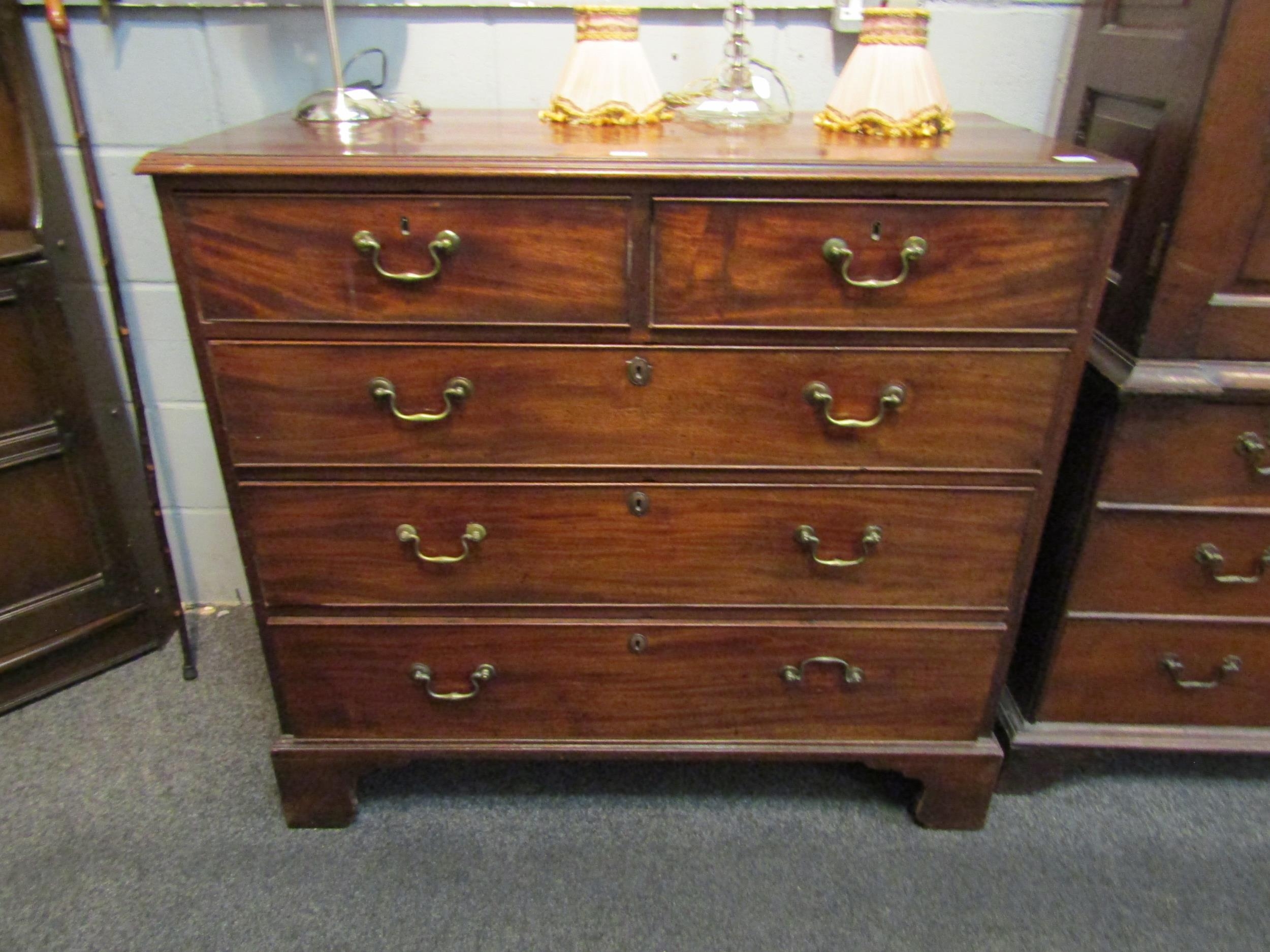 A George III mahogany chest of two short over three long drawers, brass swan neck handles, on
