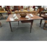 An early 20th Century oak drop leaf dining table with turned supports on castors