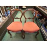 A pair of Victorian mahogany spoon back chairs with carved back rests over serpentine front seats on