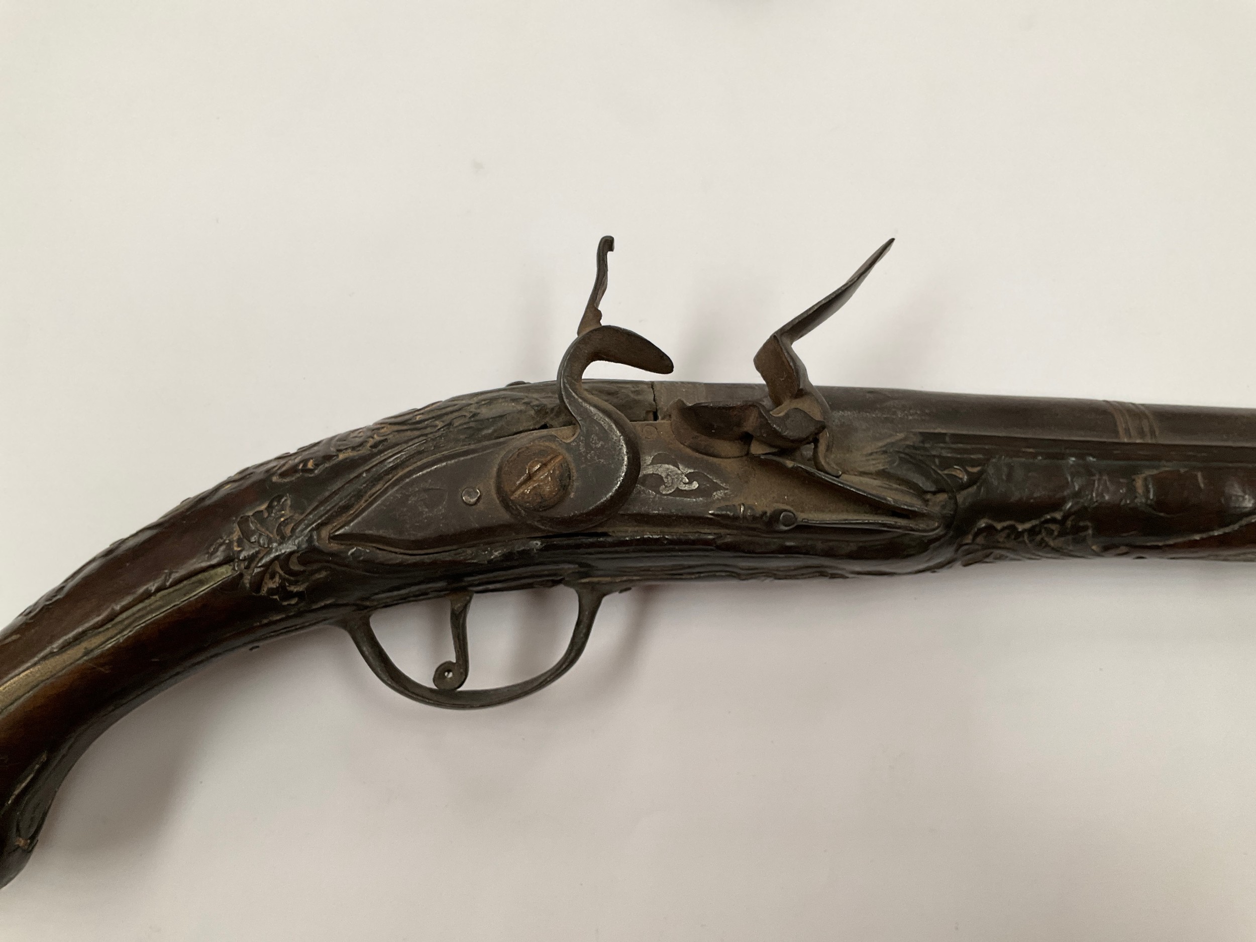 A late 18th Century flintlock pistol with all over scrolled foliate carving, part of mechanism