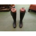 A pair of black riding boots and wooden boot trees