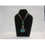 A white metal multi strand pendant necklace with turquoise droplets