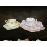 A Foley china Art Nouveau quattro cup and saucer set with mauve floral design and an earlier trio (