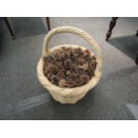 A large handled wicker basket containing a quantity of pine cones