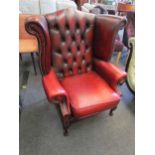 A Chesterfield style red leather two seater sofa together with a wingback armchair on cabriole