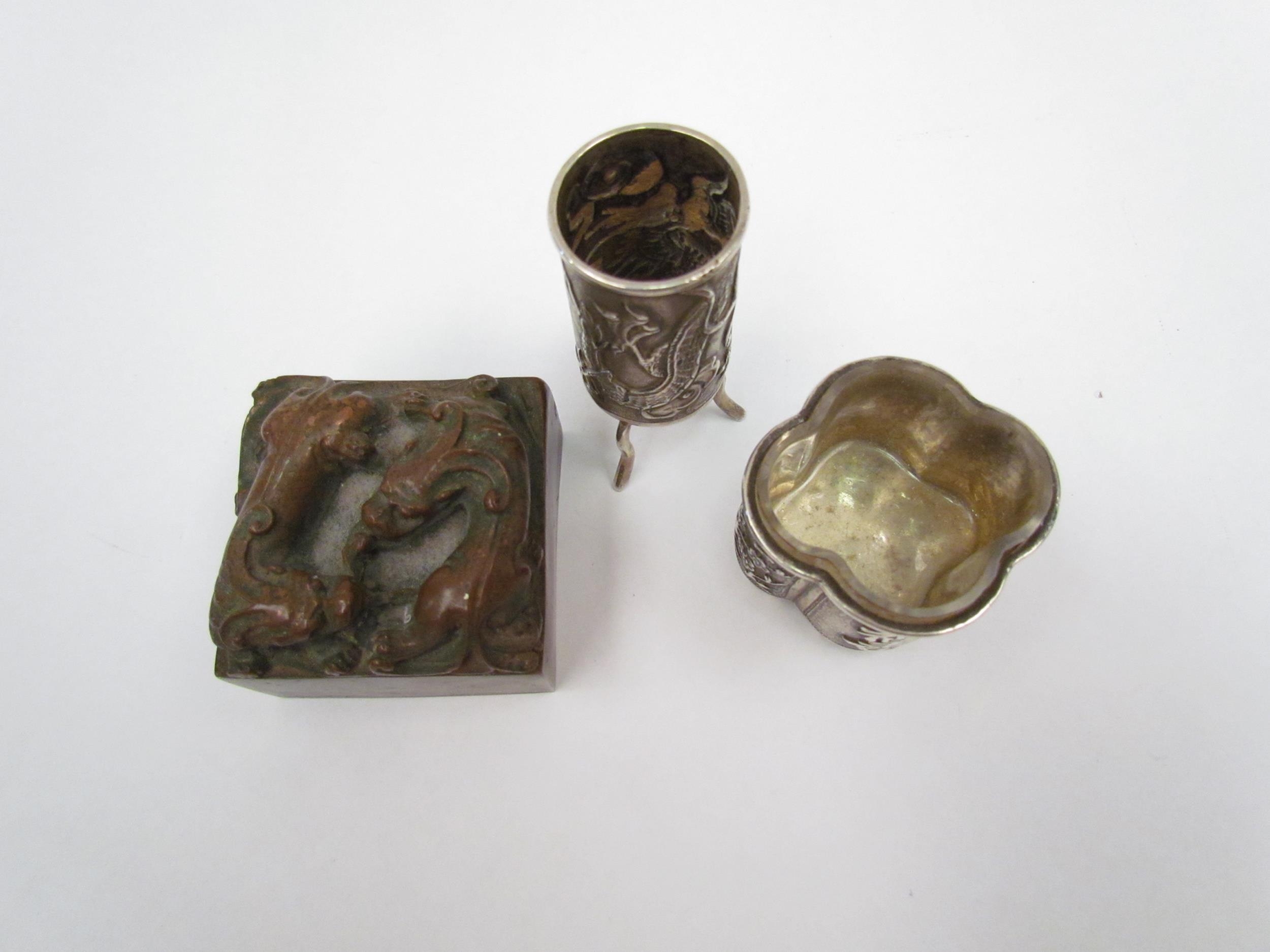 Two Chinese white metal items, a salt with exterior scenes and a miniature vase on tripod feet