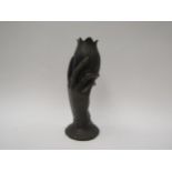 A hollow cast metal vase of a hand holding a tulip