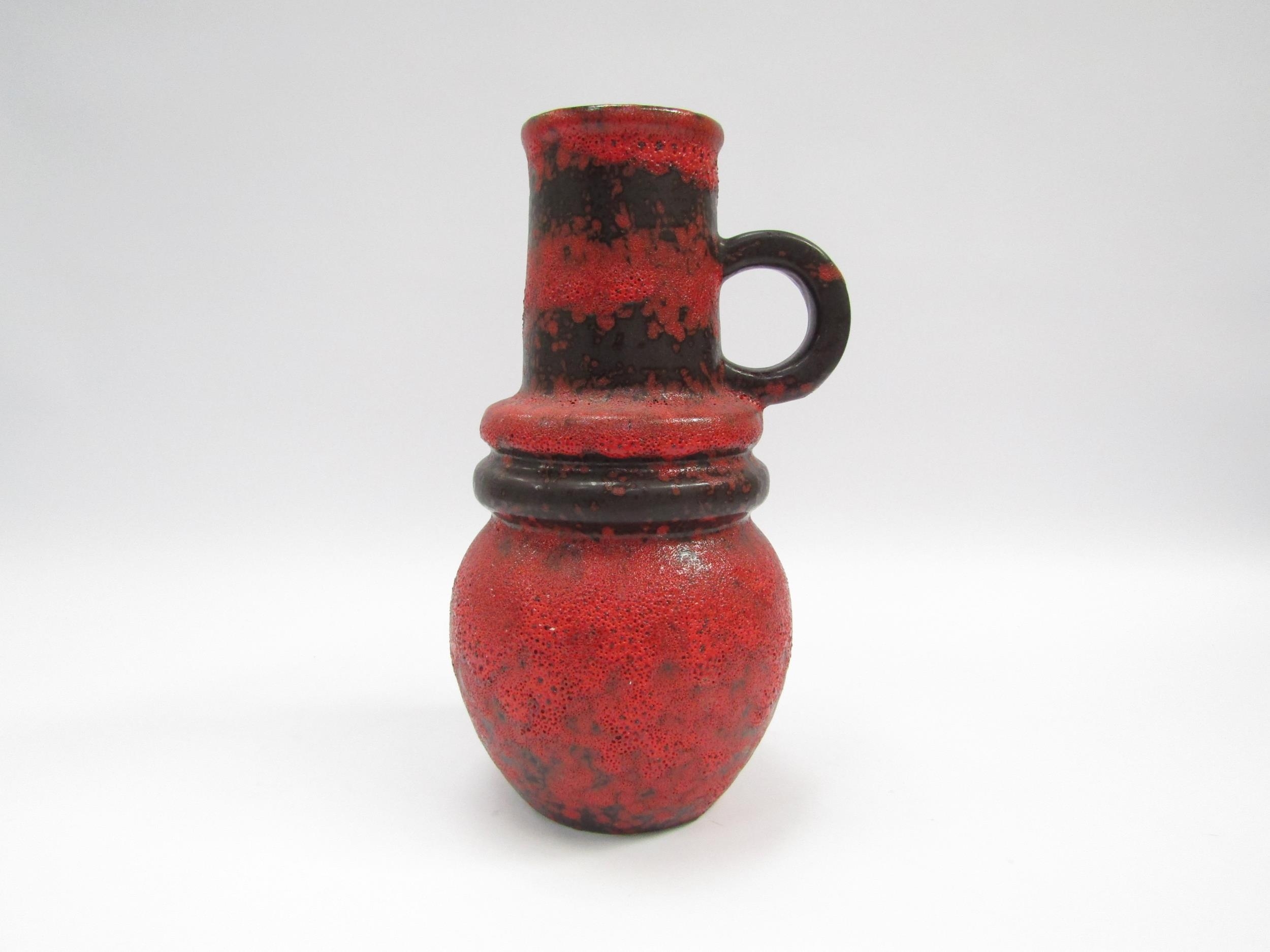 A West German Scheurich vase with single handle and hooped centre in fat lava red and black glaze,