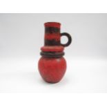 A West German Scheurich vase with single handle and hooped centre in fat lava red and black glaze,