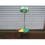 A 1950's standard lamp, black metal frame with three colored top sliding table base and magazine