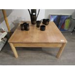An Ercol beech coffee table on cylindrical legs, 69cm squared.