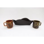 Two Hornsea Pottery mugs with Griffon and Hen designs. Together with a black glazed waved trough