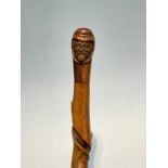 A knarled twisted wood walking cane with carved double ended mask of a man, 92cm long