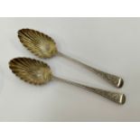 Two similar London assayed Georgian serving spoons with shell form bowls and bright cut handles,
